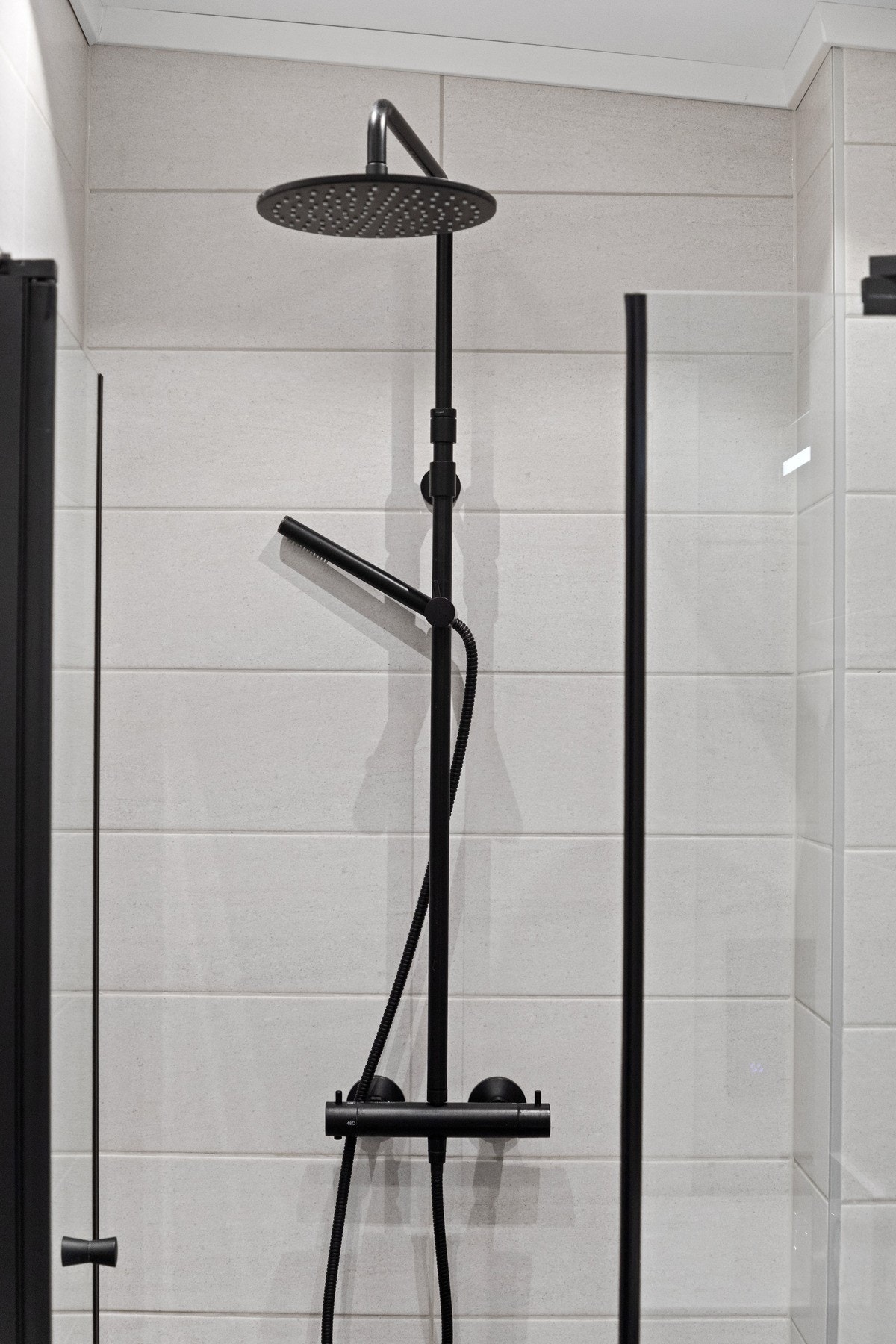 Innredningen består av en heldekkende servant på hvit skuffeseksjon, speilskap med integrert belysning, et veggmontert toalett, og en dusjnisje med glassdører, regnfallsdusj og hånddusj. Galleribilde