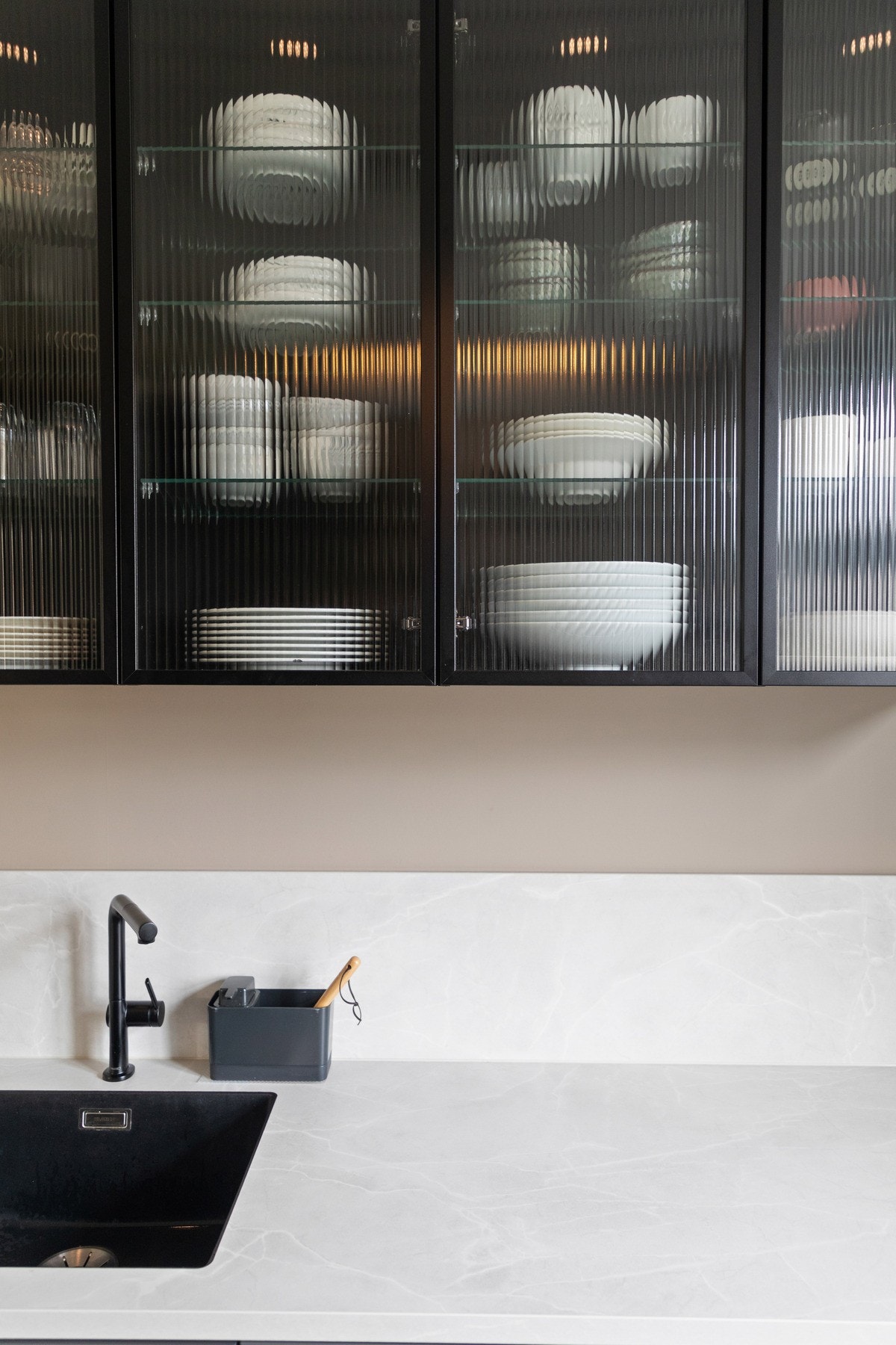 Innredningen har glatte fronter i en peppergrå farge, vitrineskap og lekker benkeplate av laminat med nedfelt oppvaskkum i sort utførelse. Galleribilde