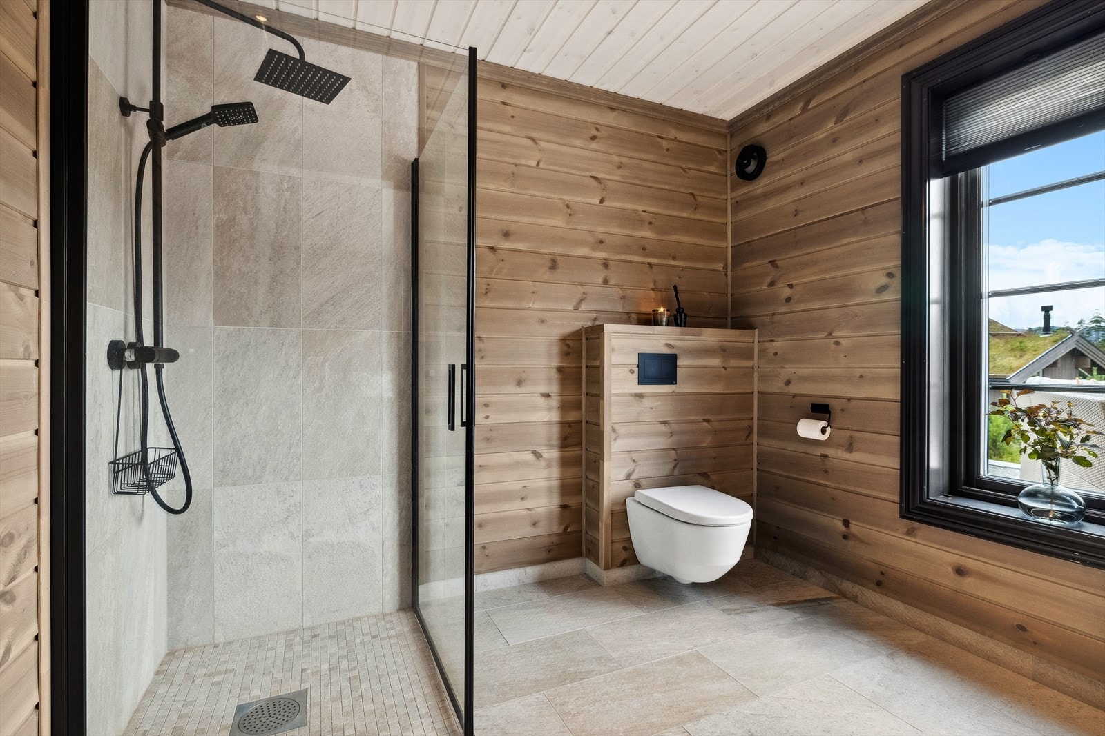 En suite baderom ved master bedroom har fine fliser på gulv og i dusj, samt panel på vegger og i himling. Galleribilde