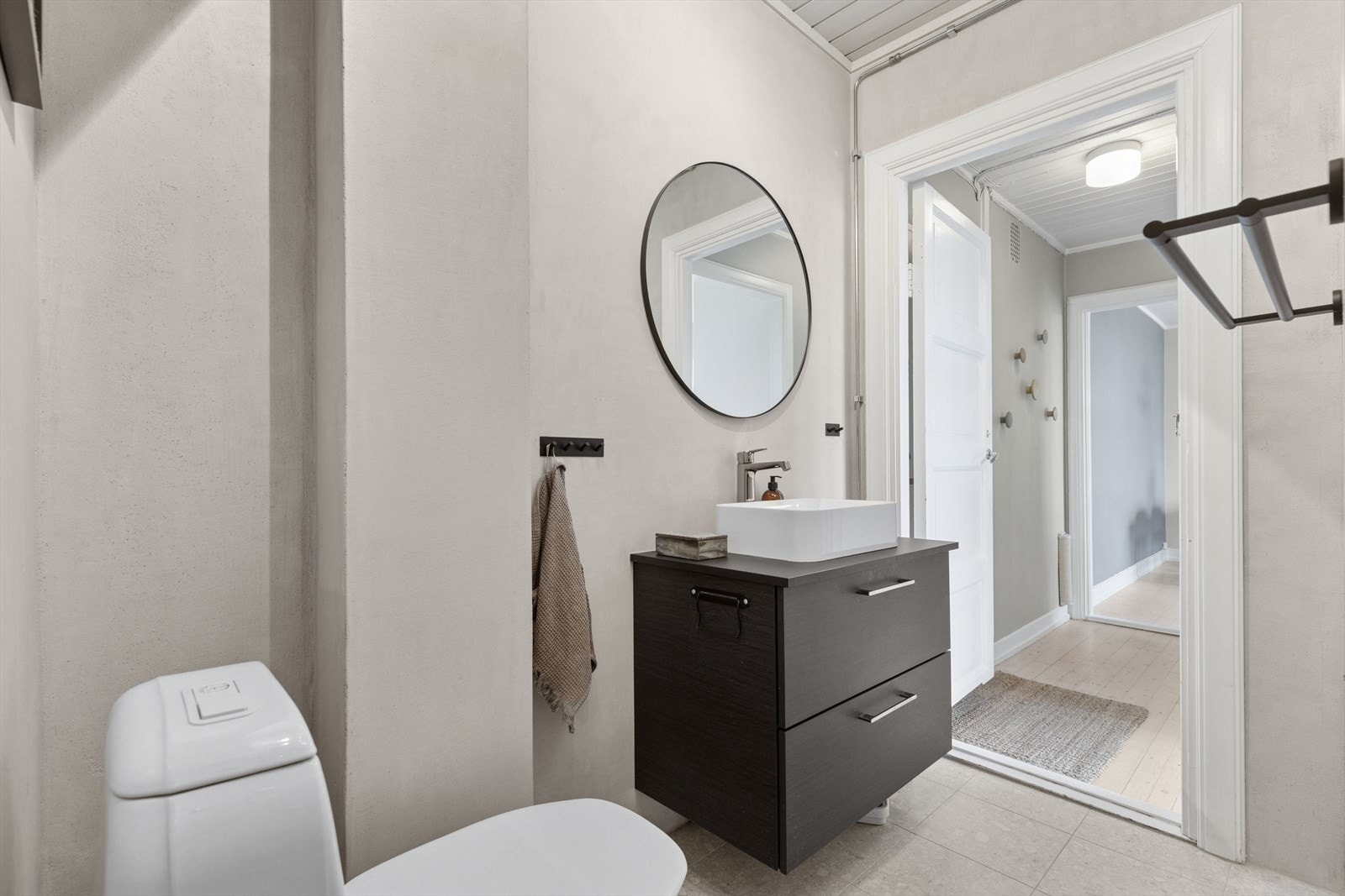 Badet inneholder frittstående toalett, dusj, servant med ett-greps blandebatteri og servantskap. Galleribilde