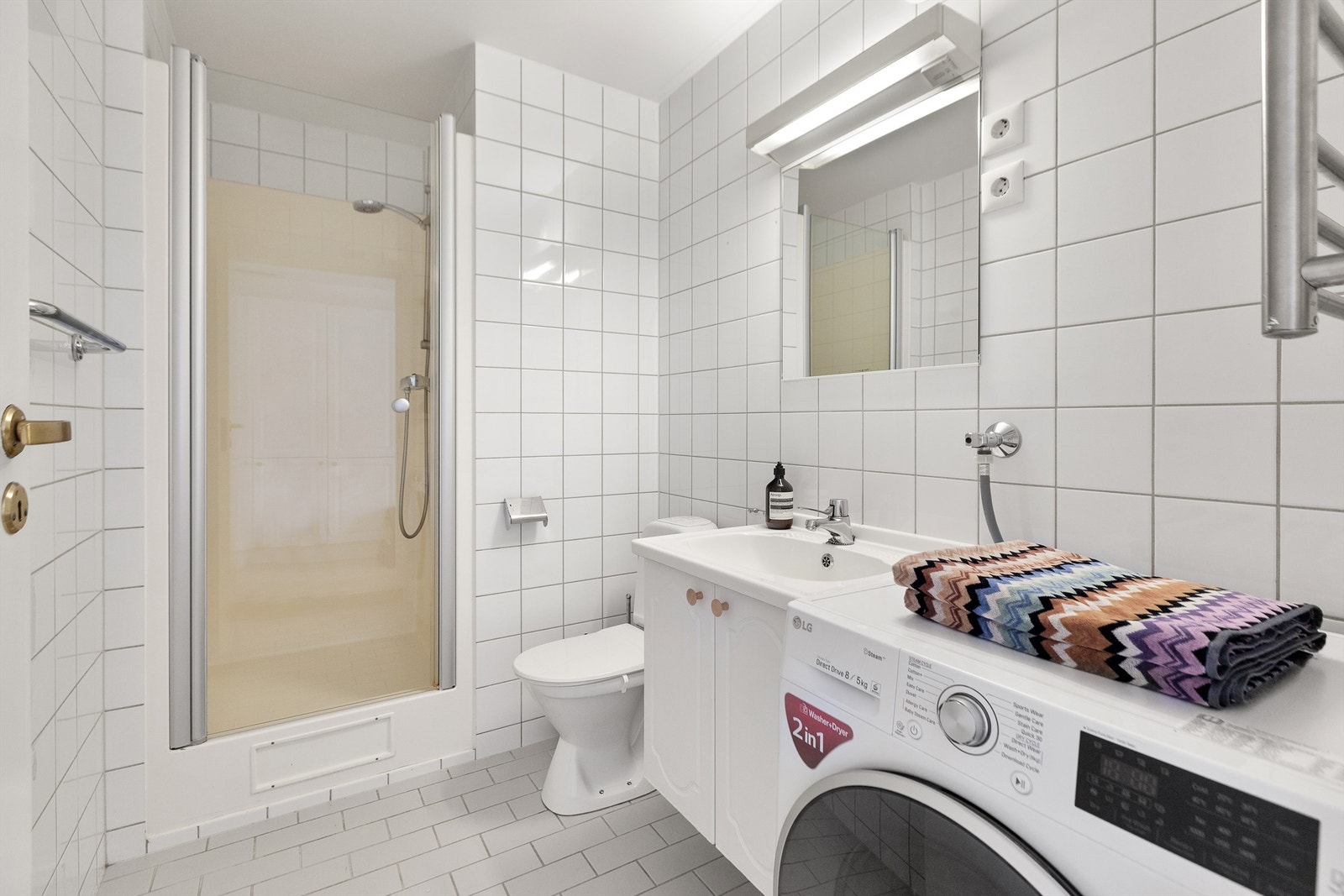 Badet med standard fra byggeår med flislagt gulv med varmekabler og lyse flislagte vegger. Galleribilde