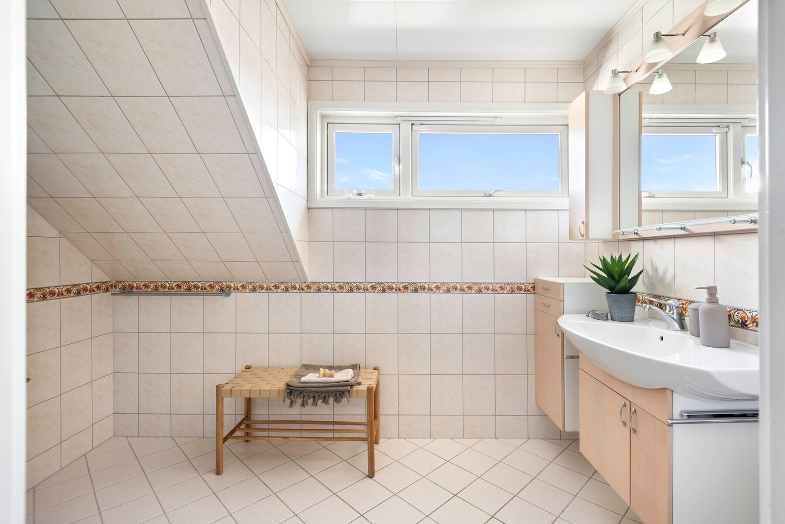 Badet har vegghengt innredning bestående av servantskap i slett utførelse med ovenpåliggende servant og speilskap med belysning. Galleribilde