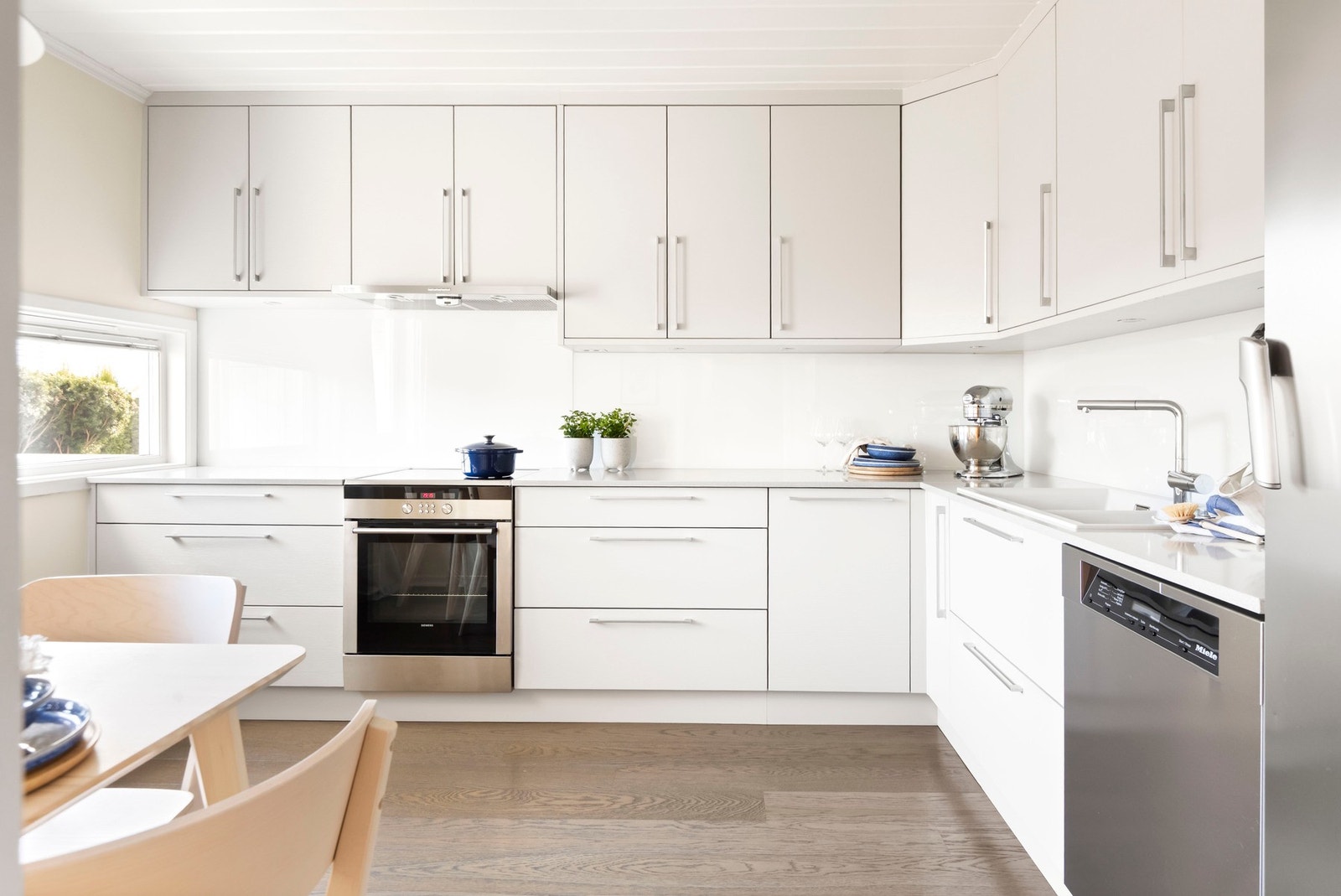 Tidløs kjøkkeninnredning med slette fronter og solid benkeplate av stein med nedfelt oppvaskkum. Galleribilde