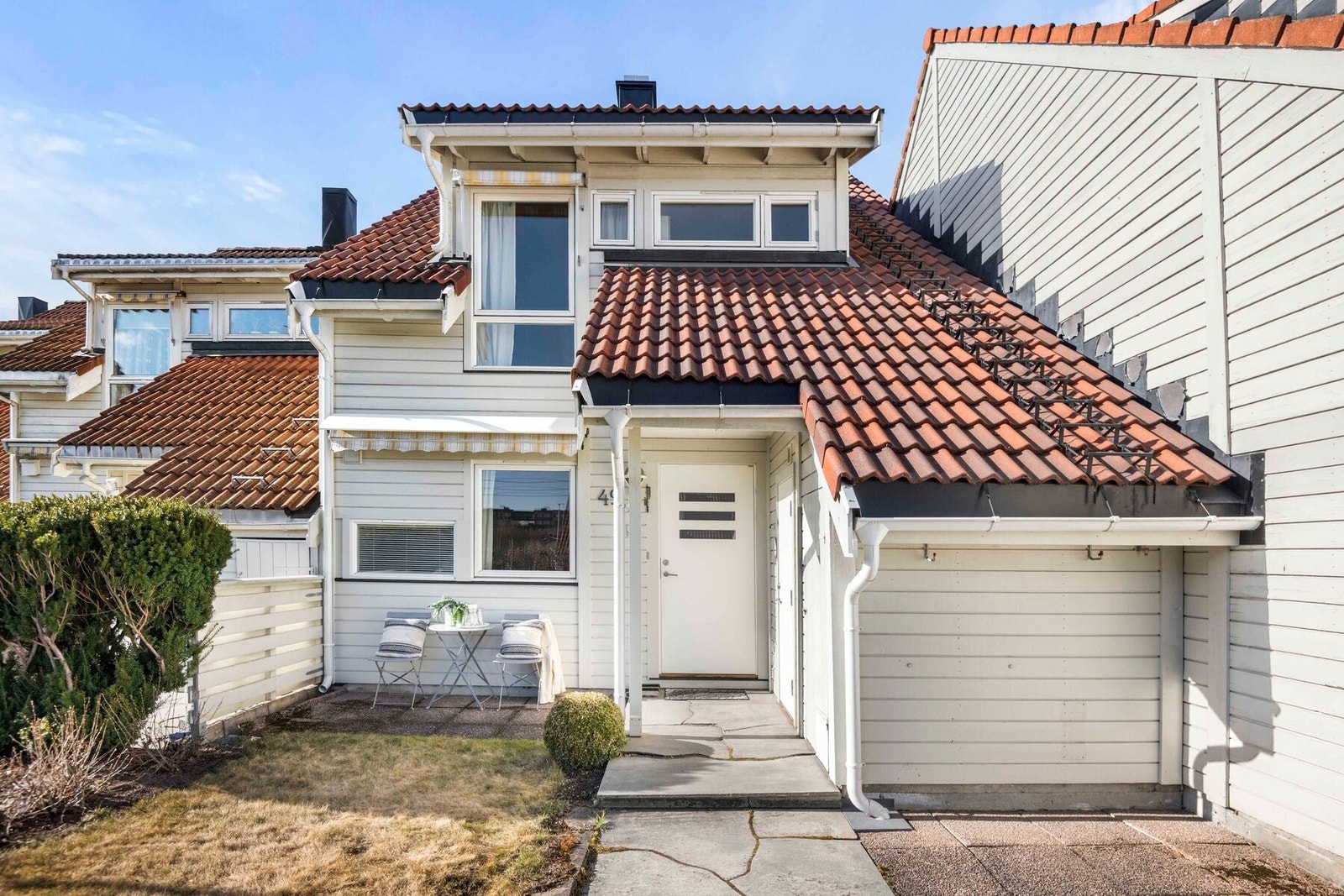 Boligen har slett entrédør med glassfelt og adkomst via forhage og eget inngangsparti på bakkeplan. Galleribilde