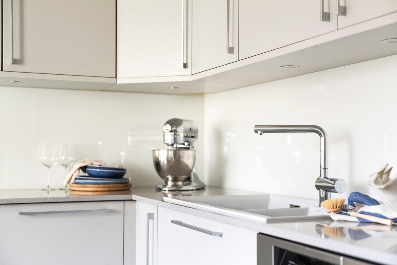 Tidløs kjøkkeninnredning med slette fronter og solid benkeplate av stein med nedfelt oppvaskkum. Galleribilde