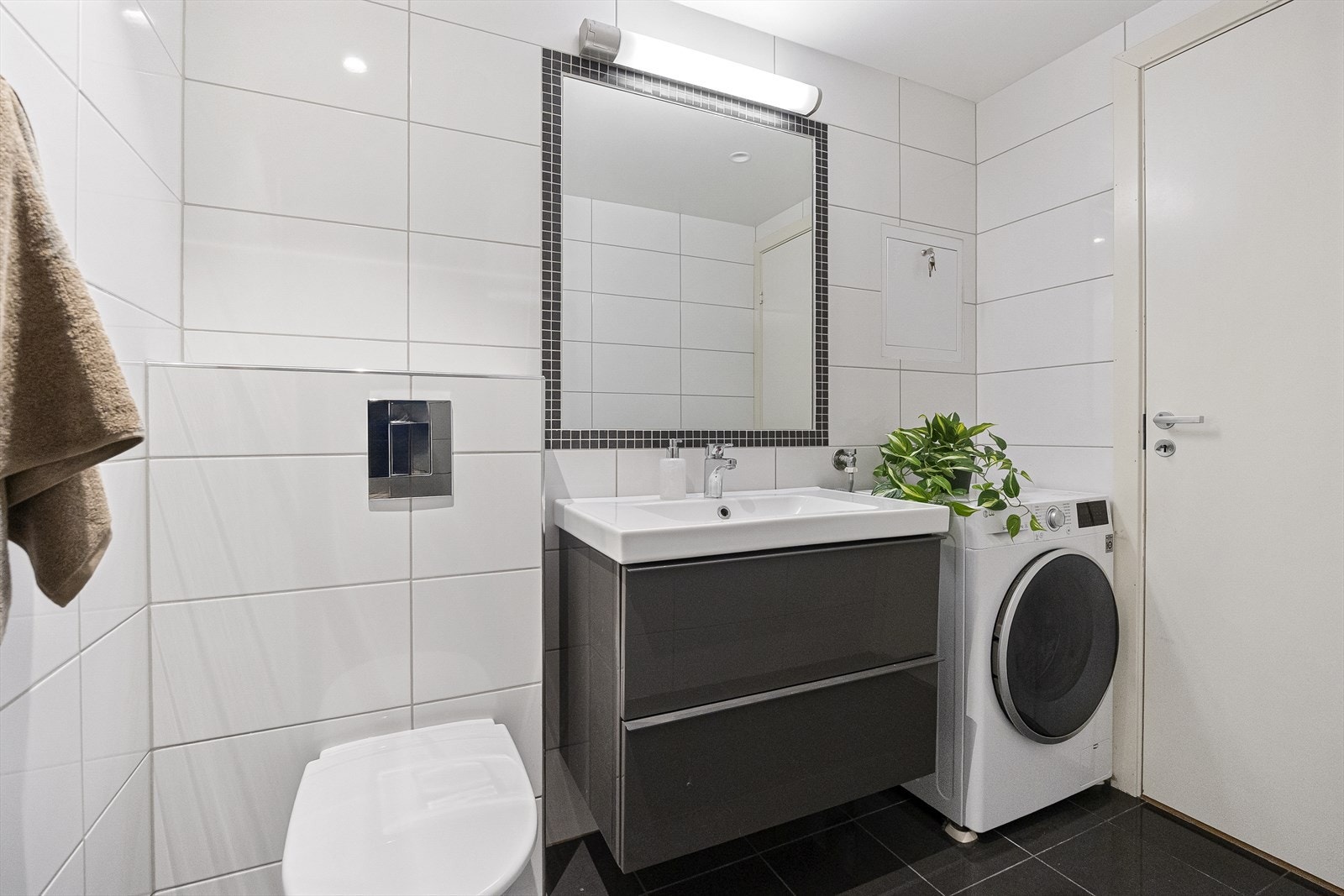 Badet er helfliset og innredet med vegghengt WC, servant med underskap, opplegg for vaskemaskin, og dusjhjørne. Galleribilde