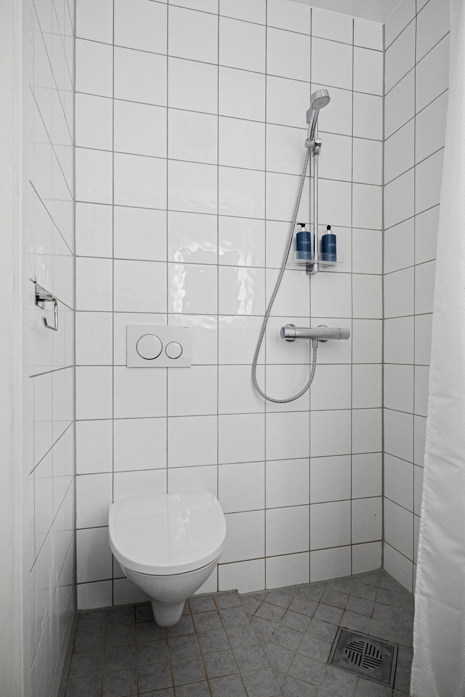 Dusjhjørne med nedsenket gulv i dusjesonen. Ett-greps dusjsjarmatur kombinert med en liten såpehylle. Galleribilde