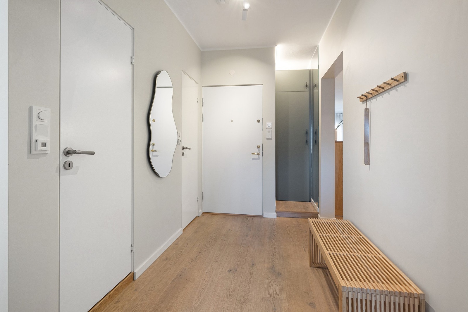 Entréen gir et svært godt førsteinntrykk med sin lyse og romslige utforming. Like innenfor døren finnes en bod med kombinert vaske-/tørkemaskin (medfølger) og hyller over, praktisk plassert og sikret med vannstoppesystem - en smart og plassbesparende vask Galleribilde