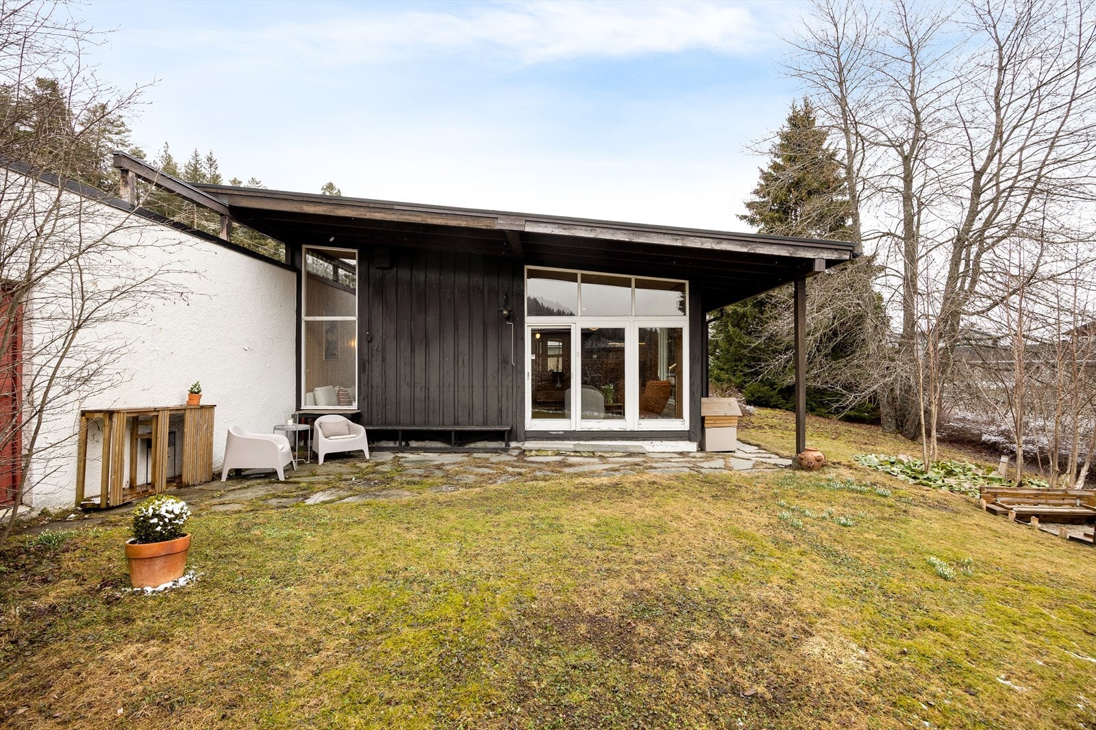 Om våren og sommeren er området rundt huset vakkert beplantet med gress, trær og frodige busker. Galleribilde