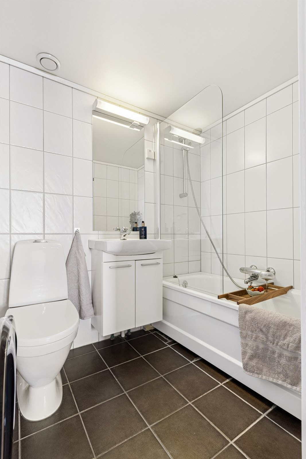 Like ved finner du badet, som er lyst og praktisk innredet med badekar, dusjgarnityr, toalett, servant og opplegg for vaskemaskin. Galleribilde