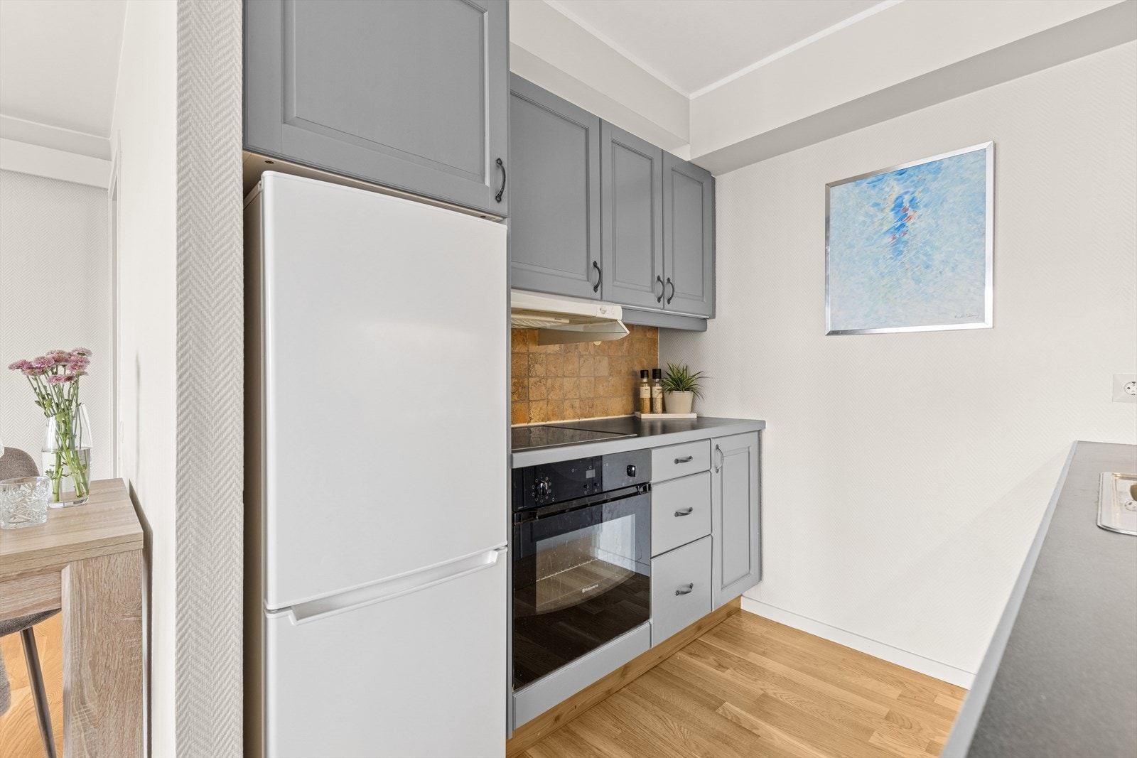 Kjøkkenet er i åpen løsning, med malte fronter og integrert platetopp, komfyr og oppvaskmaskin. Det er godt med skapplass og tilstrekkelig benkeplass, noe som gir en funksjonell og praktisk kjøkkenløsning. Galleribilde