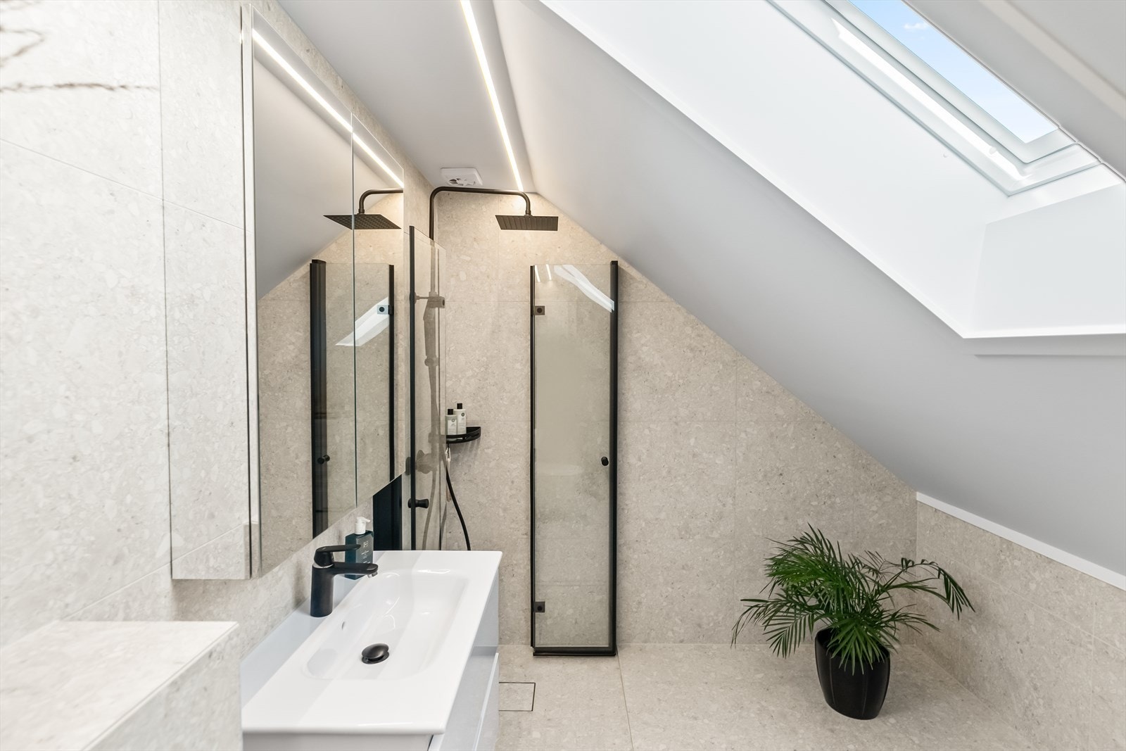 Et dusjhjørne er utstyrt med sort regnfallsdusj og innfellbare dører i sort innramming. Galleribilde