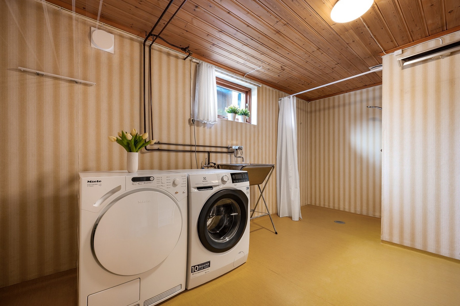 Stort vaskerom med opplegg for vaskemaskin og tørketrommel. Vaskerommet har dusjhjørne og veggmontert dusjarmatur. Galleribilde