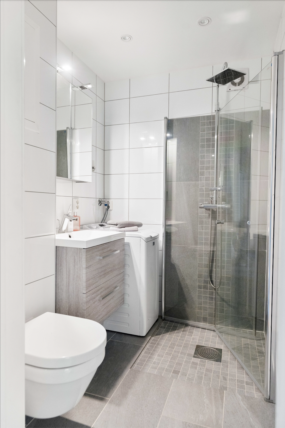 Badet fra 2016 inneholder speilinnredning med lys, vegghengt toalett og dusj i hjørne bak svingbare glassvegger. Galleribilde