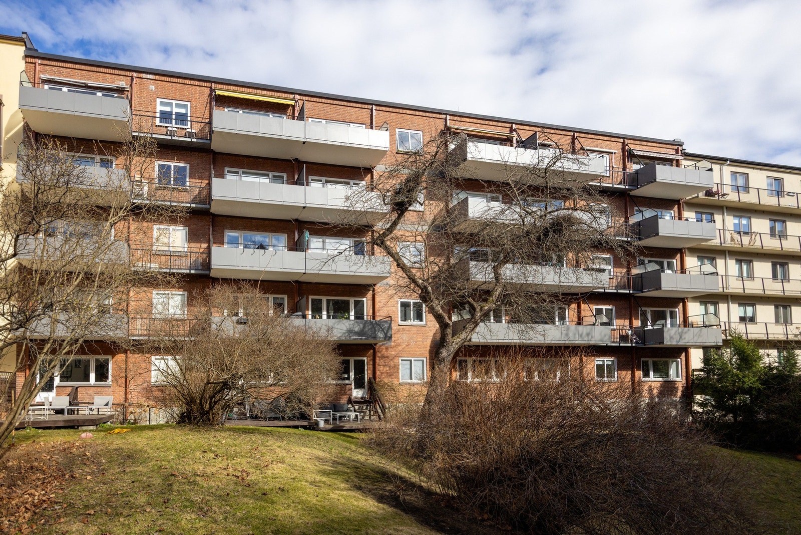 Fasade. Bakgården er pent opparbeidet med gressplen og beplanting. Galleribilde