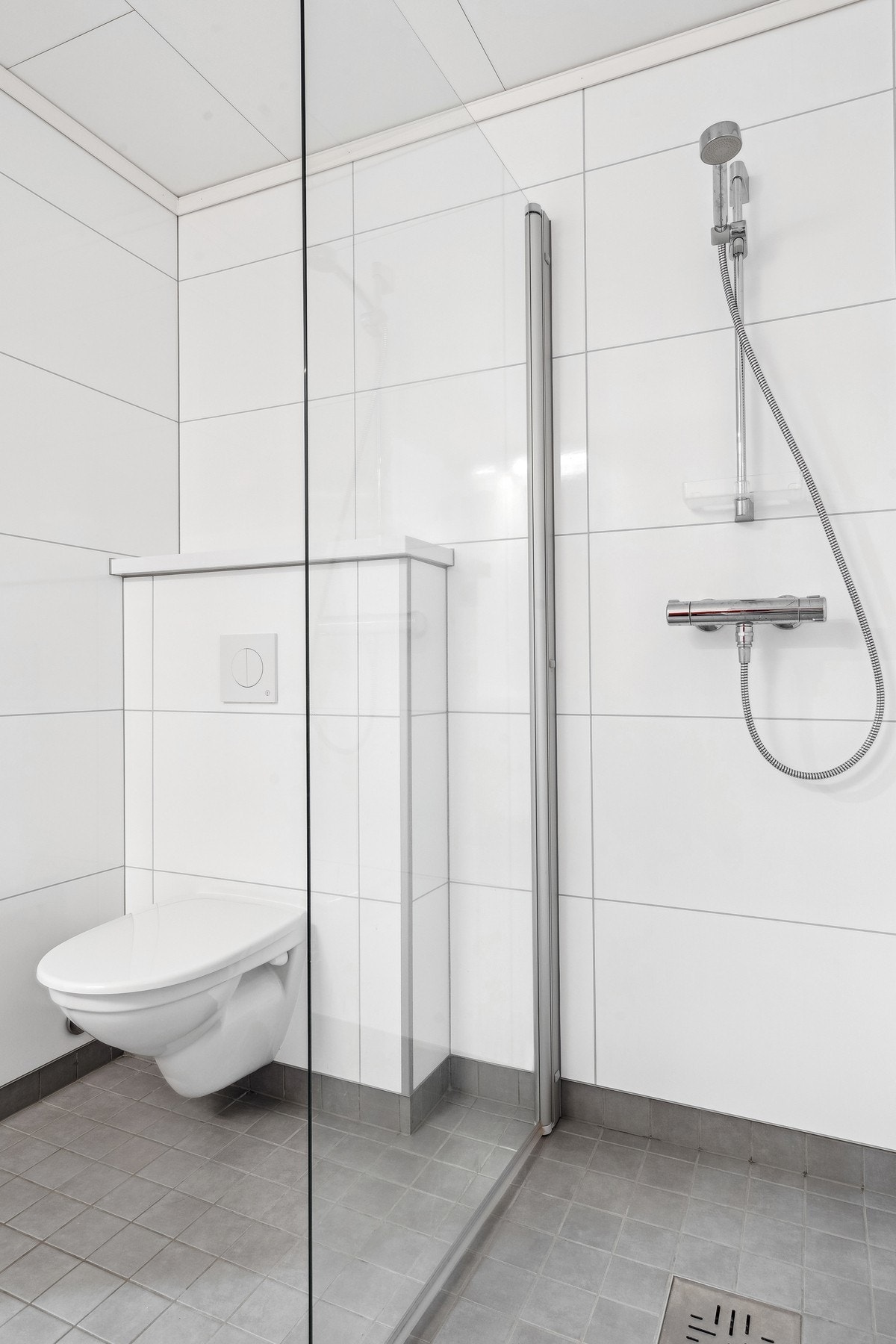 På badet er det vegghengt toalett og dusjhjørne Galleribilde