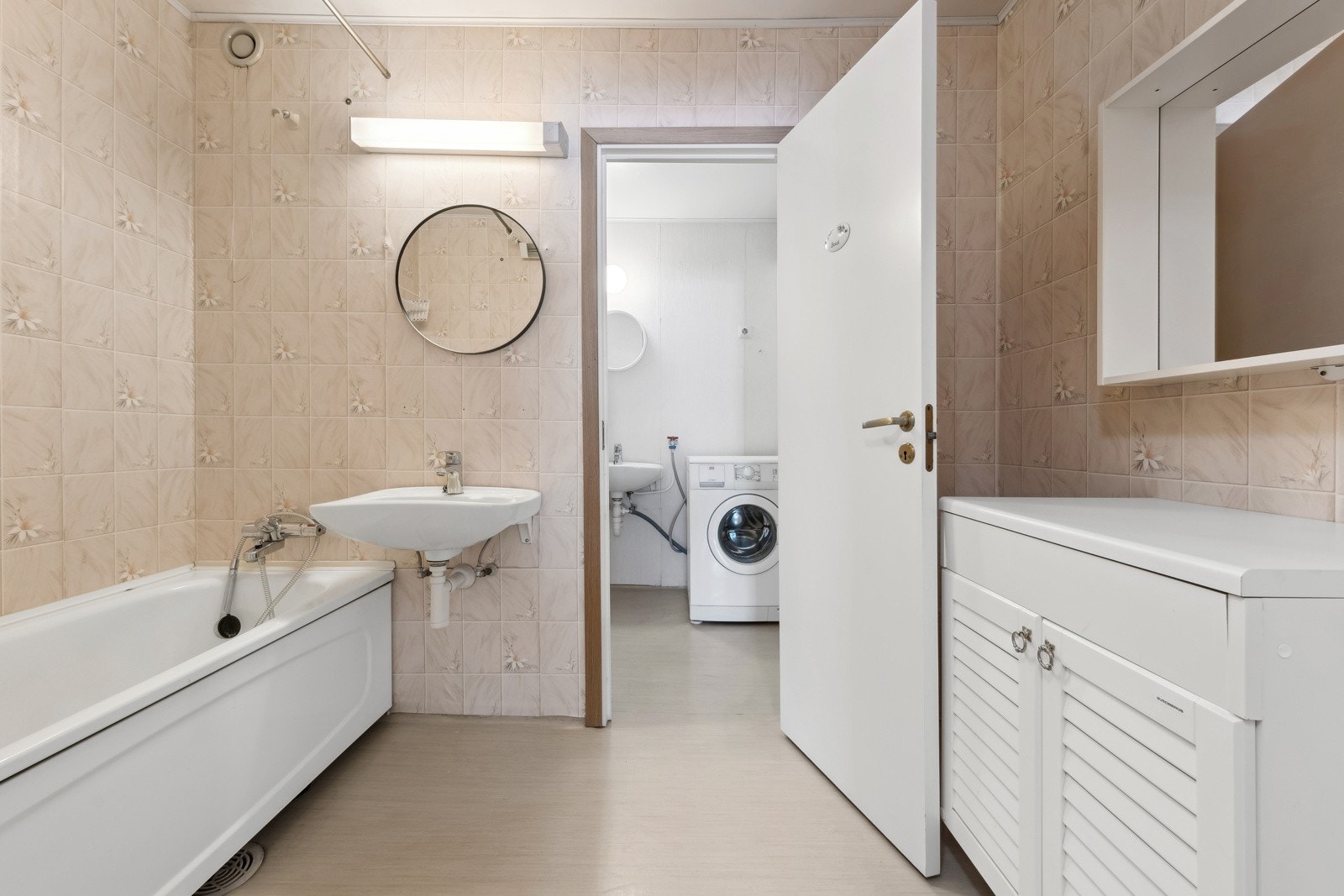 Stort baderom bestående av servant, badekar og opplegg for vaskemaskin. Galleribilde