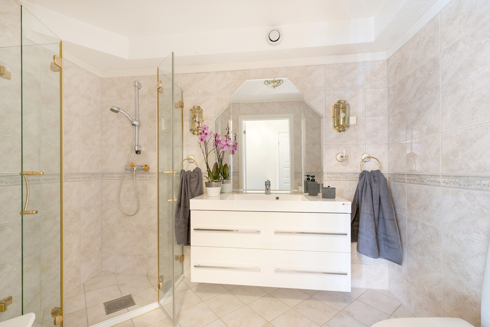 Romslig flislagt bad med dusjhjørne, servant og wc Galleribilde