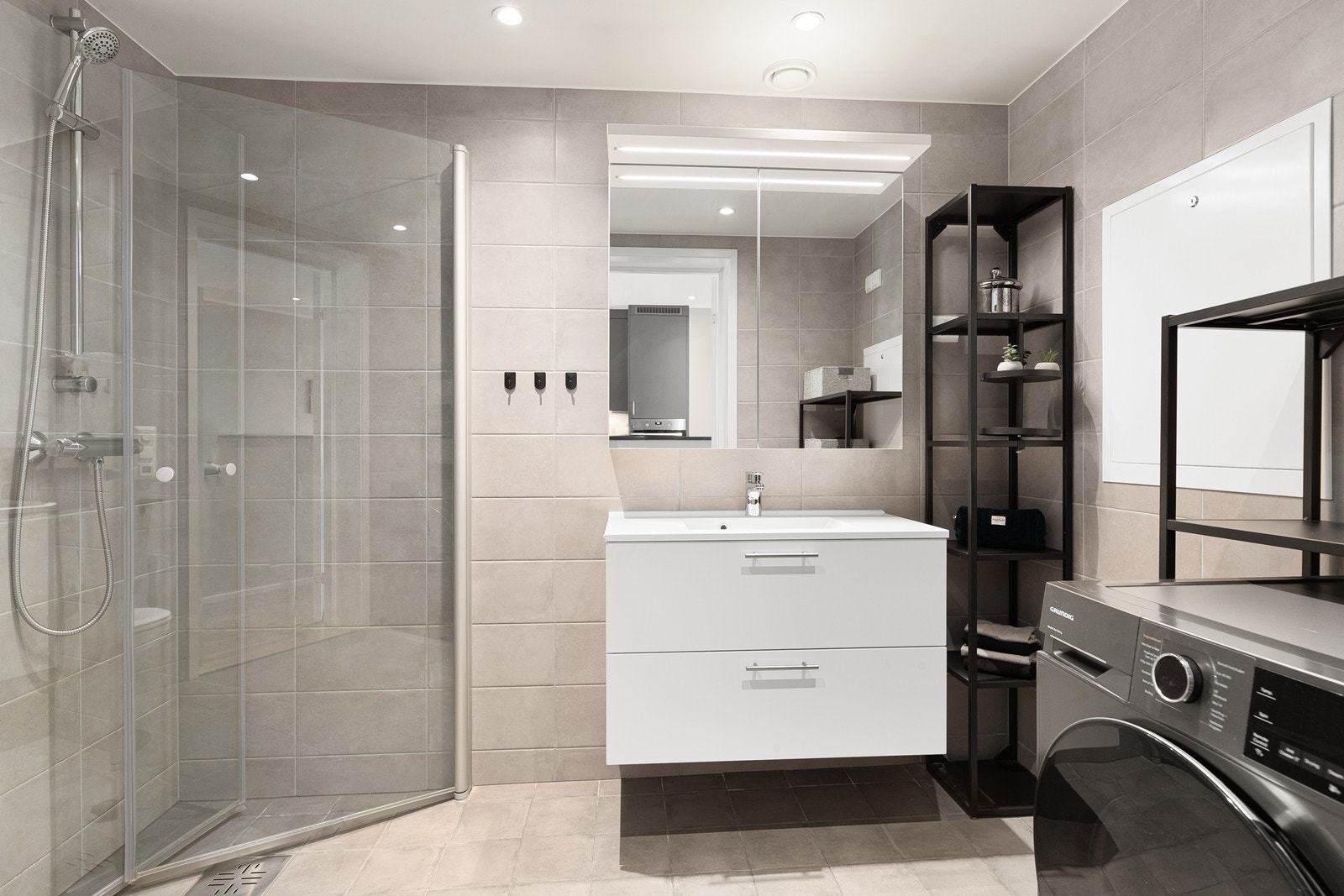 Badet er flislagt med dusjhjørne, opplegg for vaskemaskin og tørk Galleribilde