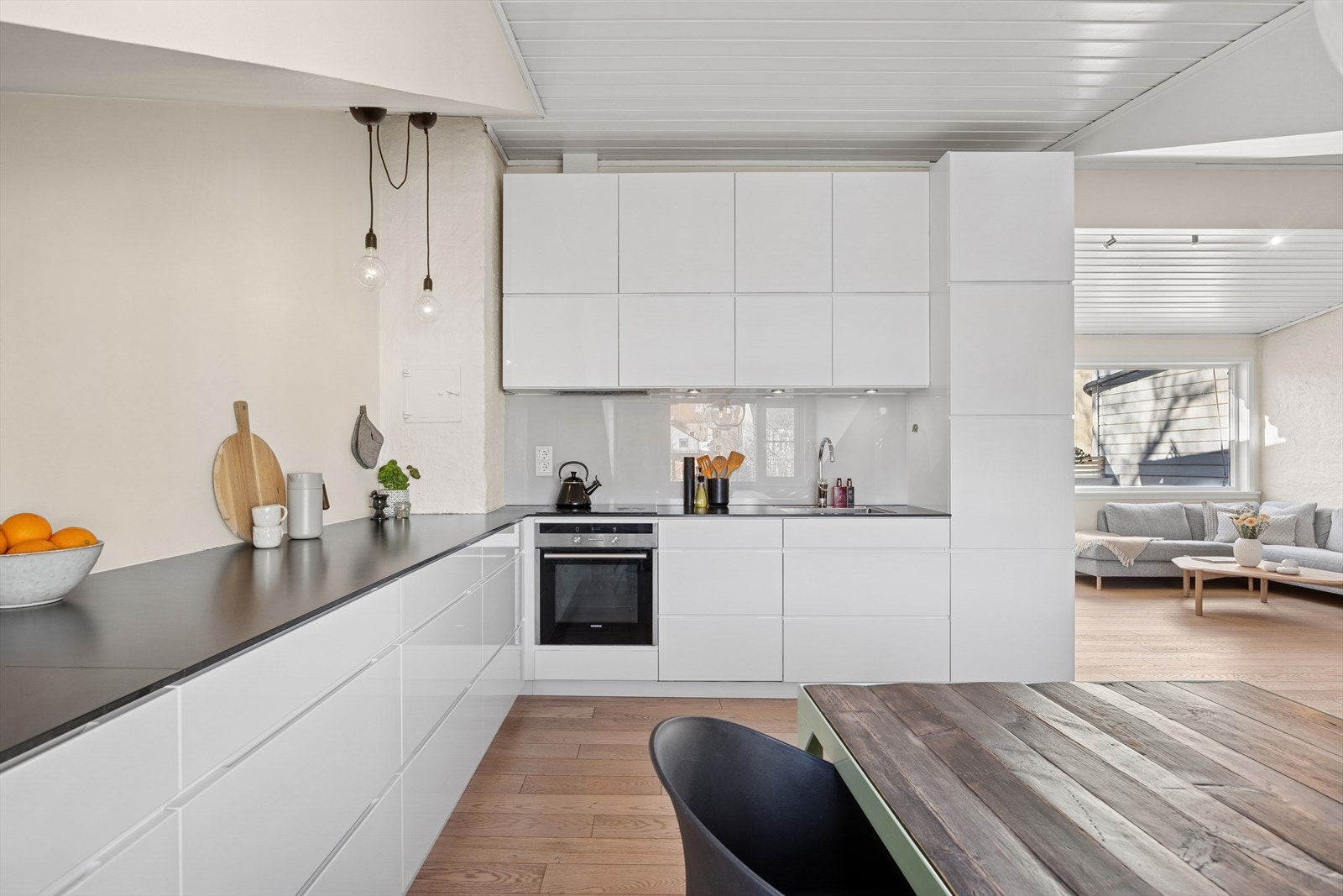 Lyst og moderne Kvik kjøkken fra 2013. Innredning med hvite, glatte fronter og Kvik Core benkeplate med underlimt oppvaskkum i rustfritt stål. Galleribilde