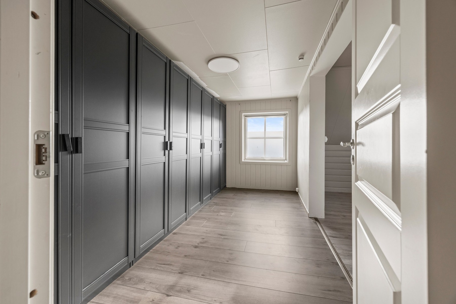 Omkledningsrom - 9,5 kvm. Praktisk garderobeløsning som strekker seg langs hele veggen. Galleribilde