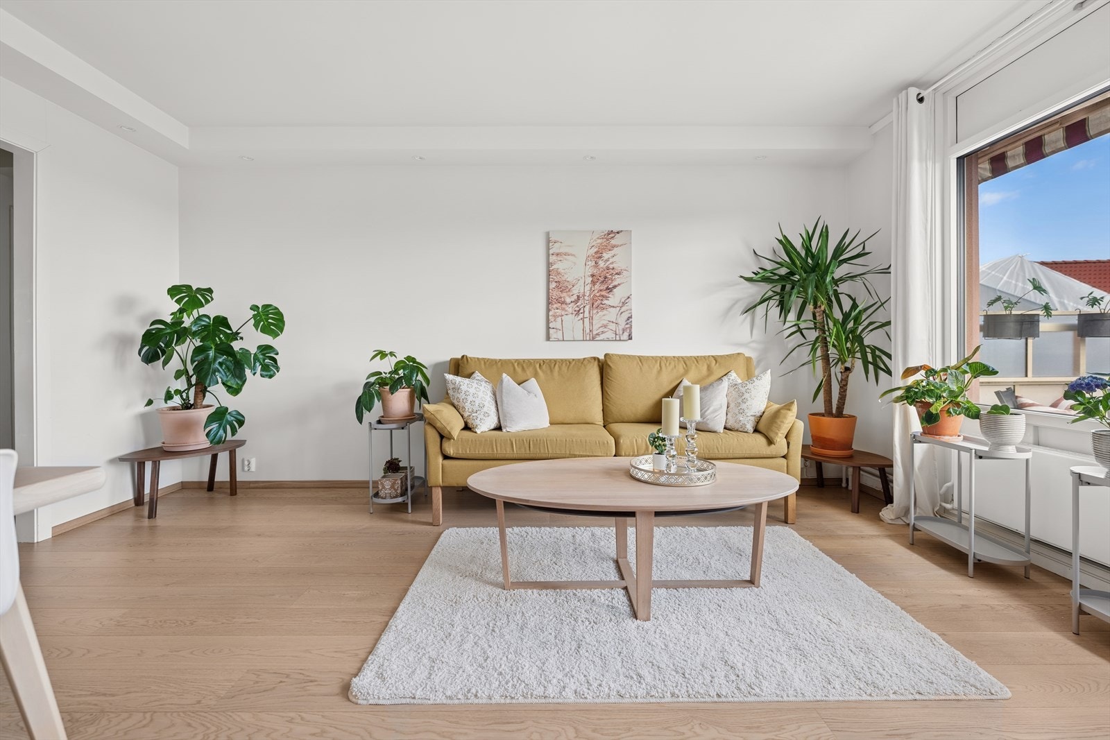 Stuens utforming gir plass til en stor sofagruppe, sofabord, og TV-løsning. I tillegg er hele stuen opplyst med downlights i kasser langs veggene, noe som skaper et lyst og innbydende miljø. Galleribilde