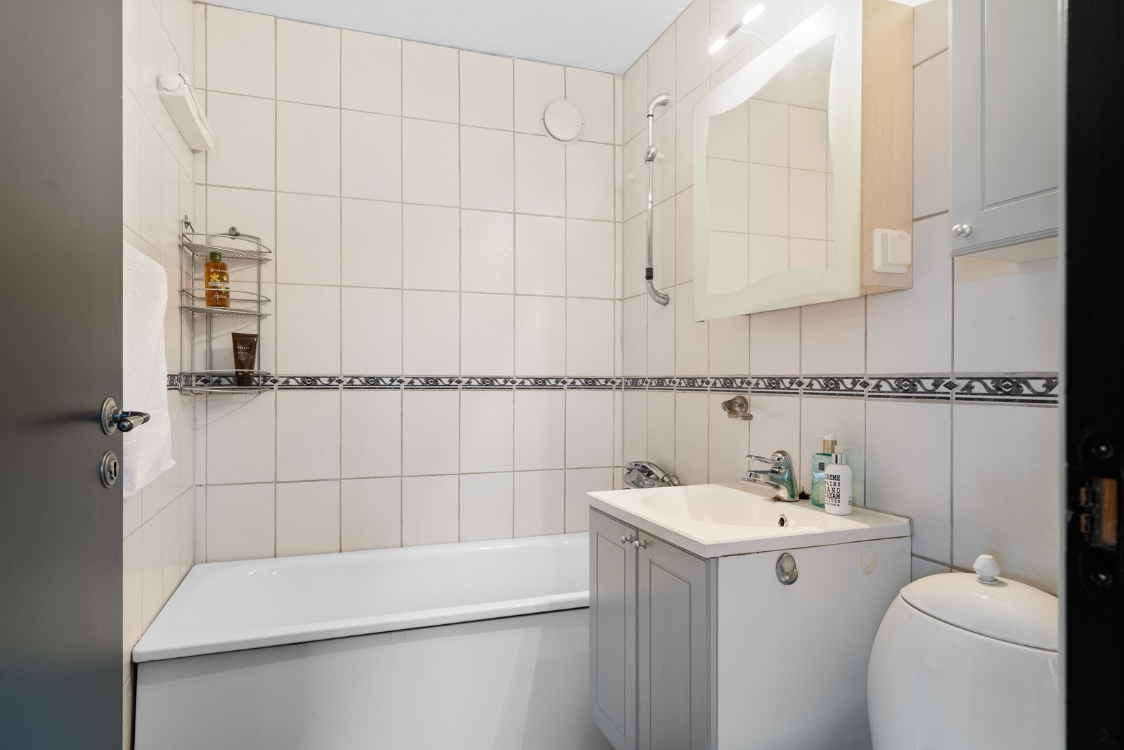 Badet er flislagt med behagelig gulvvarme. Øvrig innredning består av badekar, nedfelt servant, skap til oppbevaring og toalett. Galleribilde