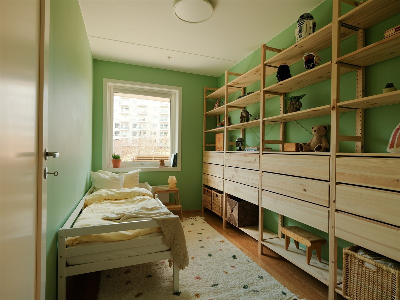 Dette soverommet har en stor hylleløsning med plass til leker, bøker og dekor, samt skuffer som gir ekstra oppbevaringsplass. Galleribilde