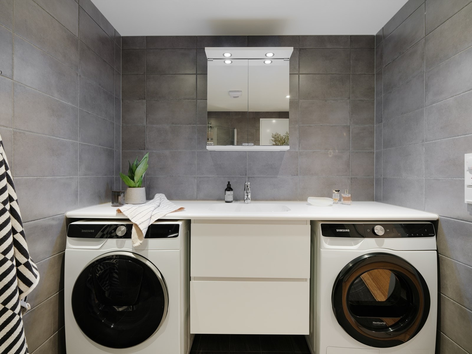 Formpresset i benkeplate med skuffer for oppbevaring under, samt opplegg for vaskemaskin og tørketrommel. Galleribilde