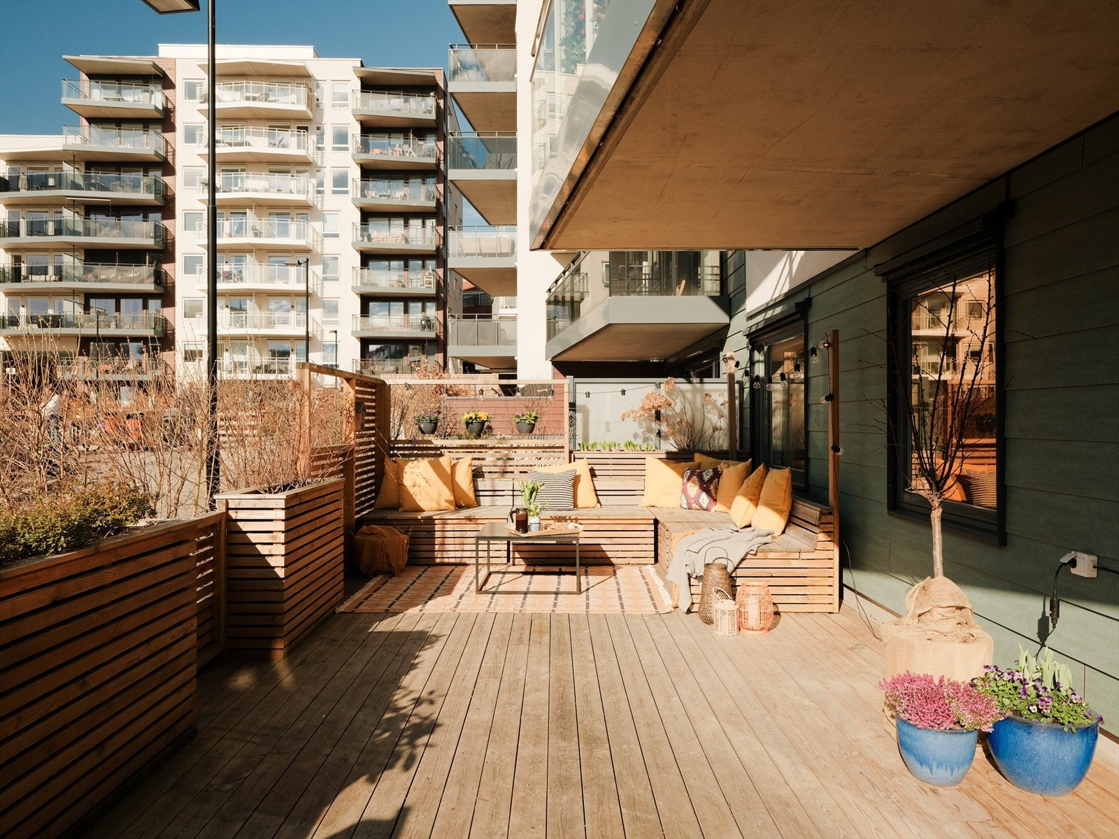 Trekonstruksjonen gir et lunt uttrykk, og plassbygde blomsterkasser tilfører et grønt og dekorativt element. Galleribilde