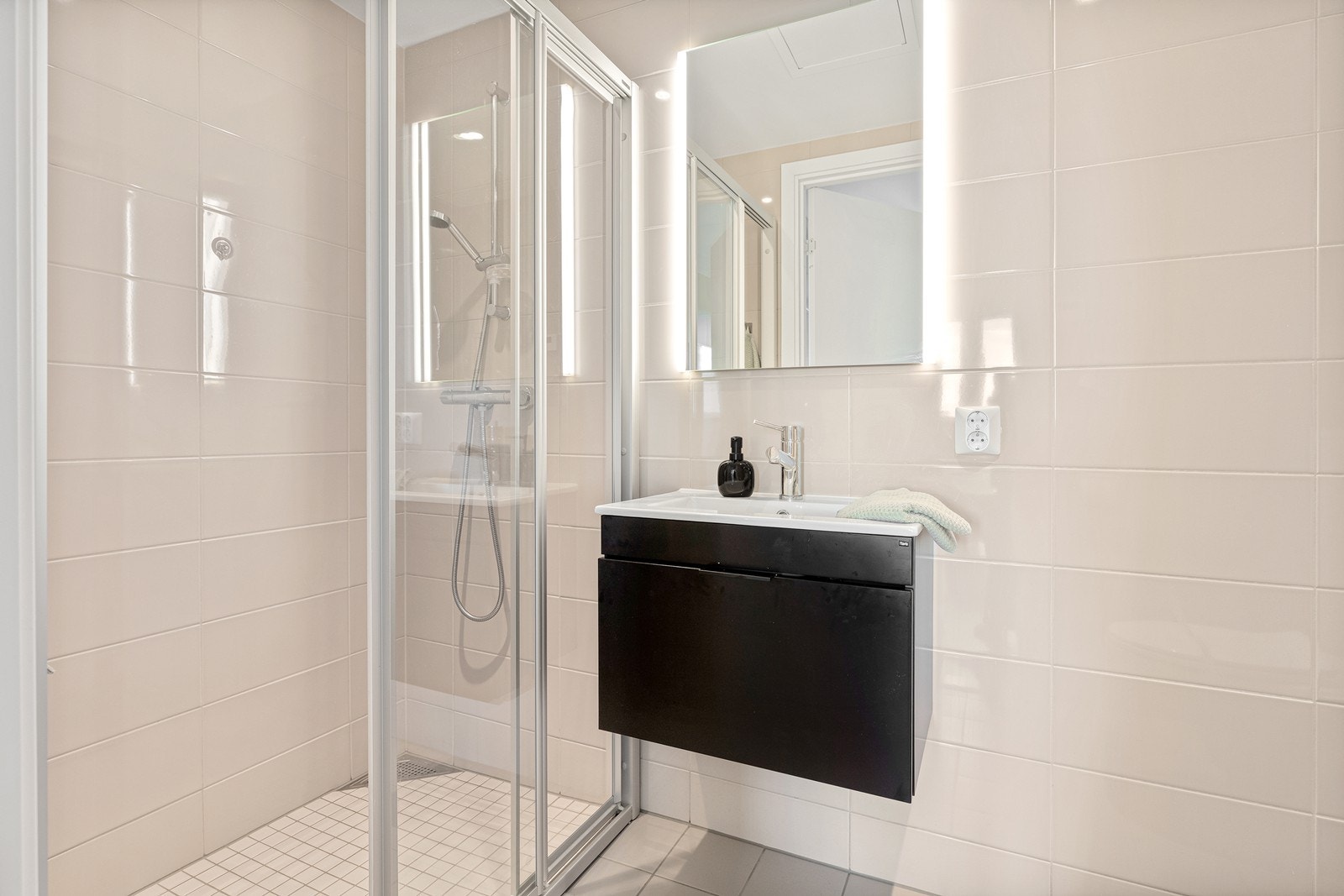 Det andre badet er tilknyttet soverommet. Badet er flislagt med gulvvarme og har vegghengt toalett, dusj med dusjvegger samt servantskap i sort utførelse og speilskap. Galleribilde