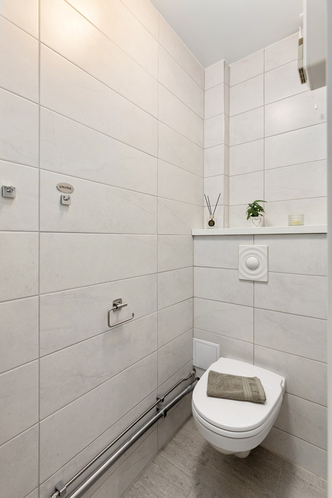 Praktisk og separat WC-rom med veggmontert toalett og servant med ettgreps blandebatteri integrert i innredningen Galleribilde