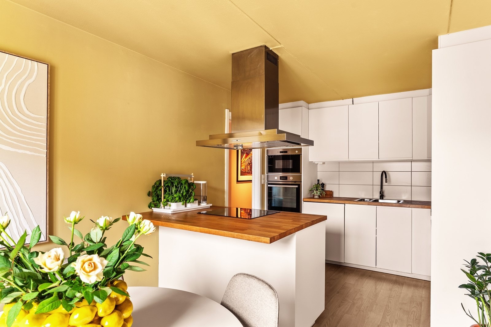 Delikat og stilrent IKEA-kjøkken fra 2018, innredet med over- og underskap samt en lekker kjøkkenøy med hvite fronter. Benkeplaten er i heltre og har en dobbel oppvaskkum med ettgreps blandebatteri med uttrekkbar spylefunksjon. Galleribilde