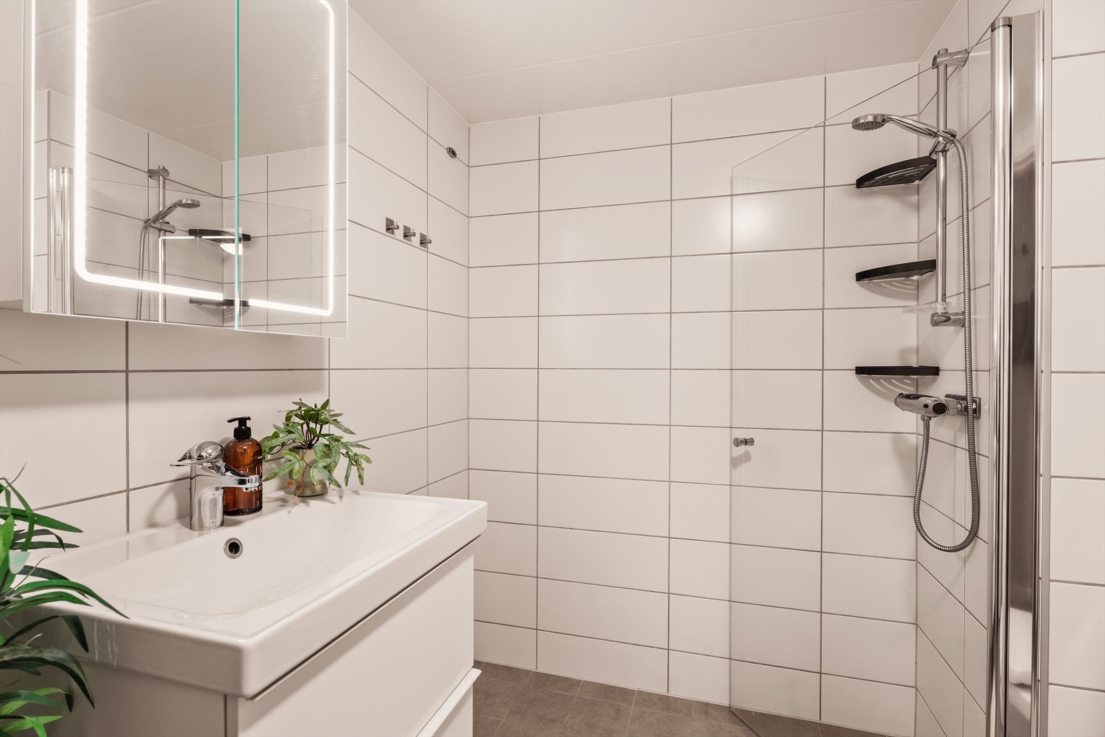 Badet er innredet med servantskap med skuffer og en heldekkende servant med ettgreps blandebatteri. Over servanten er det et speilskap med integrert belysning. Videre inneholder badet et gulvstående toalett samt et dusjhjørne Galleribilde