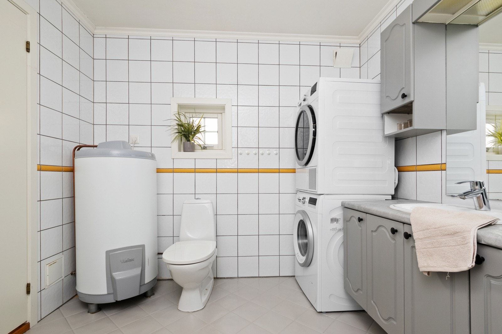 Badet fremstår som velholdt og fint, med hvite fliser på veggene og gråmalte fliser på gulv med gulvvarme. Galleribilde