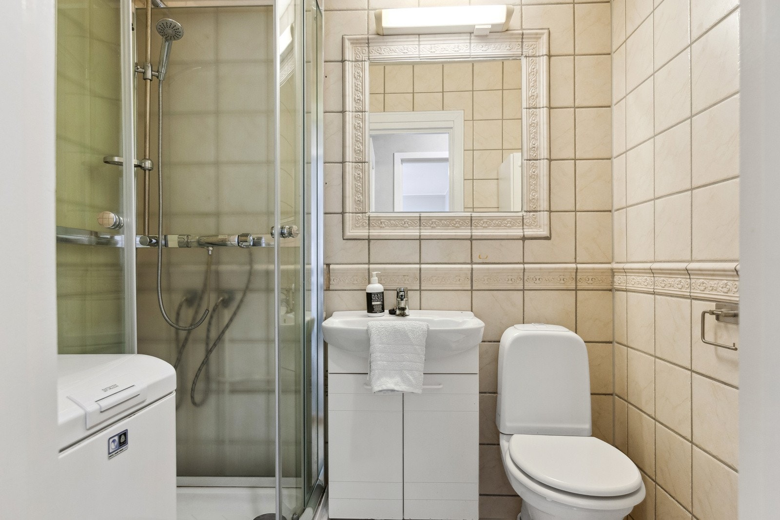 Badet er flislagt med gulvvarme, i tillegg er det dusjkabinett og opplegg for vaskemaskin. Galleribilde