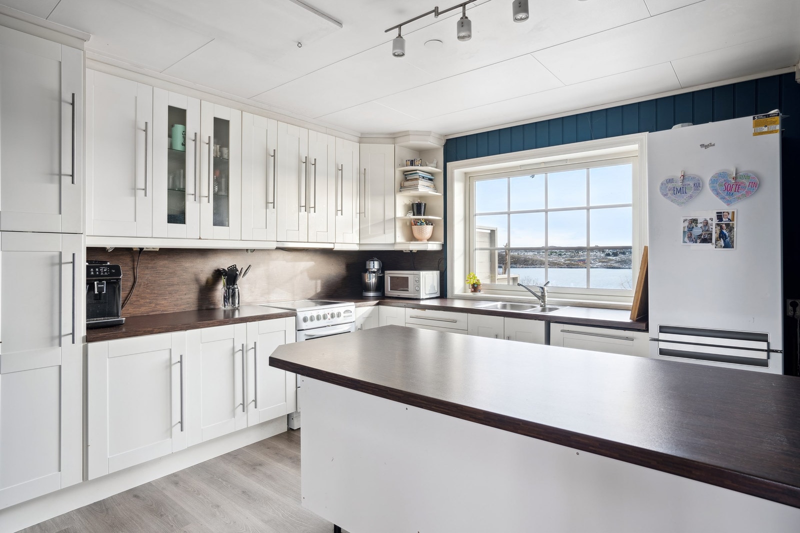 Kjøkkenet har en åpen løsning, med stilfull innredning med profilerte fronter og benkeplate i laminat. I tillegg har kjøkkenet en praktisk kjøkkenøy som skaper ekstra arbeidsplass. Galleribilde