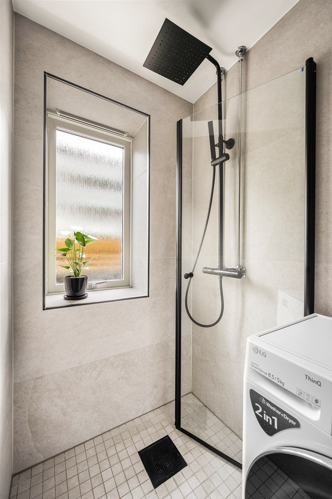 Stilrent design med heldekkende servant over innredning med suffer, speilskap med lys, vegghengt toalett og dusjsone med hånd- og regndusj. Det er opplegg for vaskemaskin. Galleribilde