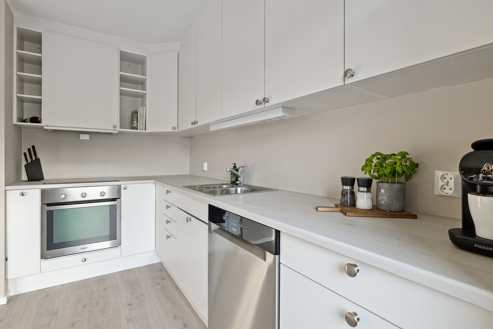 Pent Sigdal-kjøkken med innredning i glatte fronter, laminert benkeplate og delvis integrerte hvitevarer Galleribilde