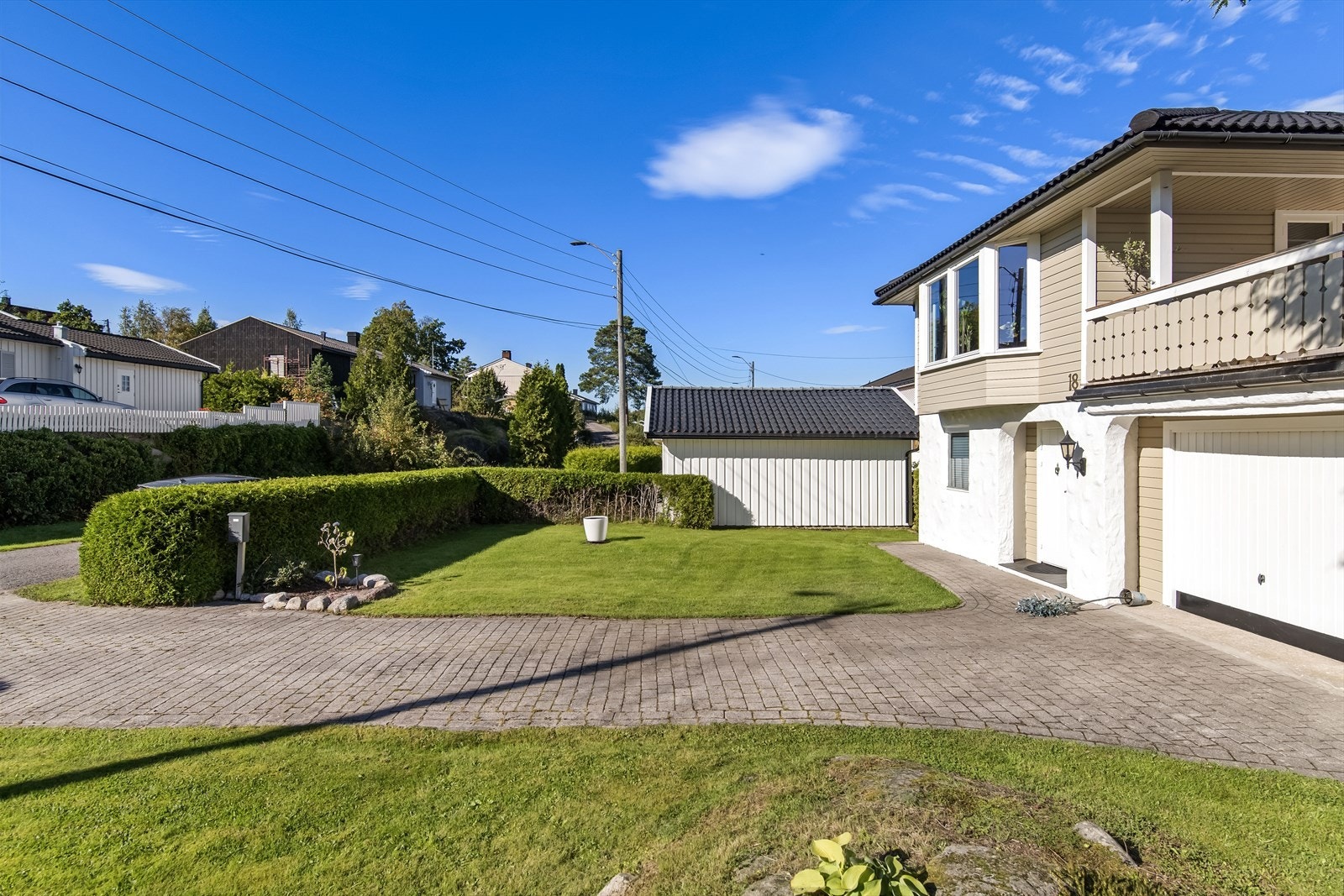 Eiendommen er pent opparbeidet med en stenbelagt innkjørsel, en velstelt gressplen og en omkransende hekk som gir både privatliv og en lun atmosfære. Galleribilde