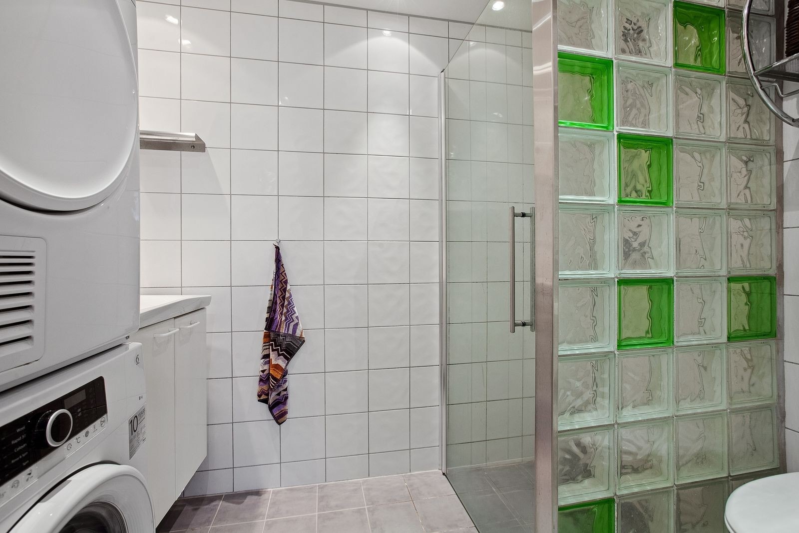 Flislagt bad med dusjvegg i glassbyggerstein og glassdør. Oppl. for vask og tørk. Galleribilde