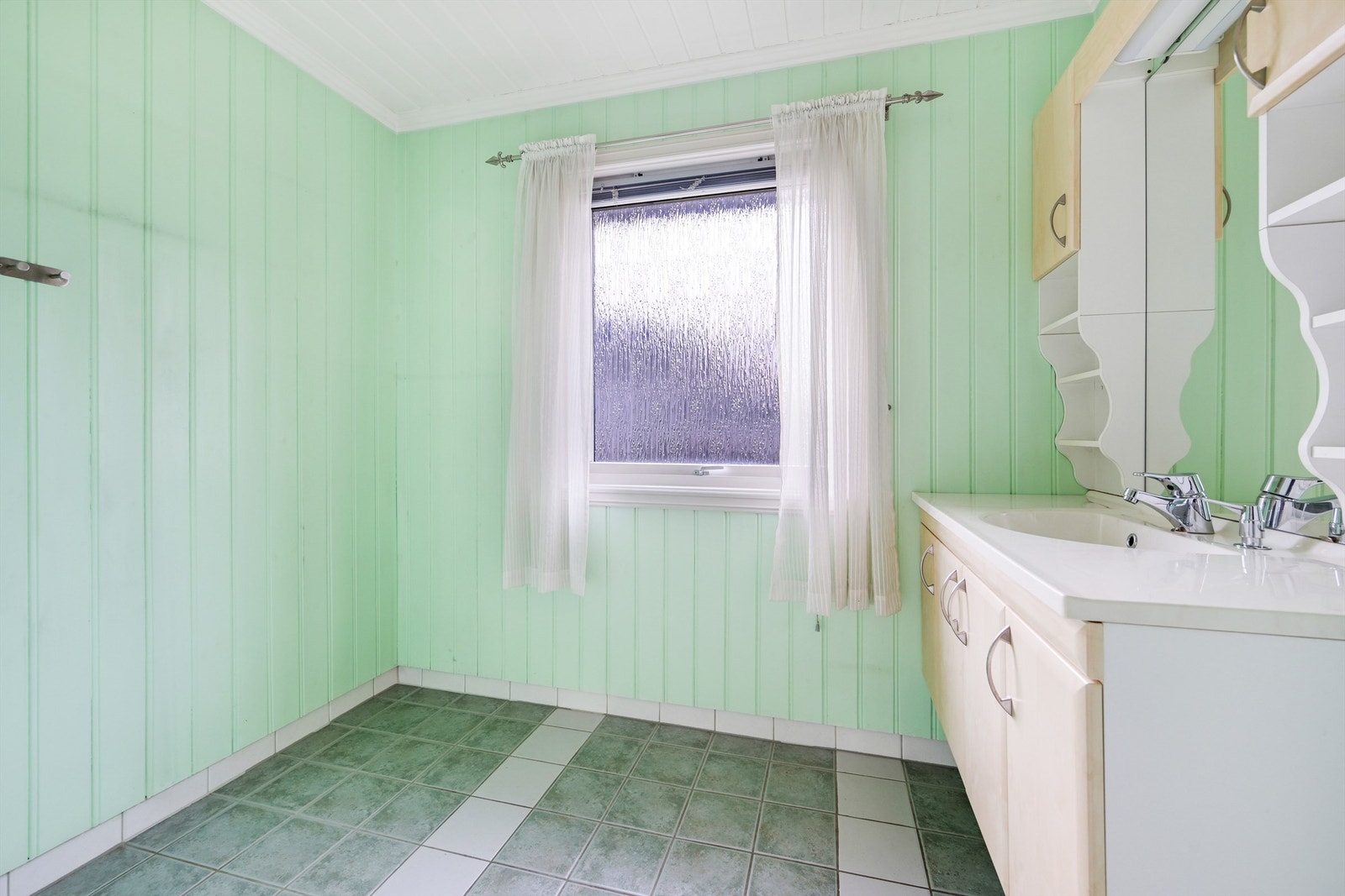 Det er nedfelt servant i baderomsinnredningen, toalett og en dusjvegg inn til dusjnisje. Galleribilde