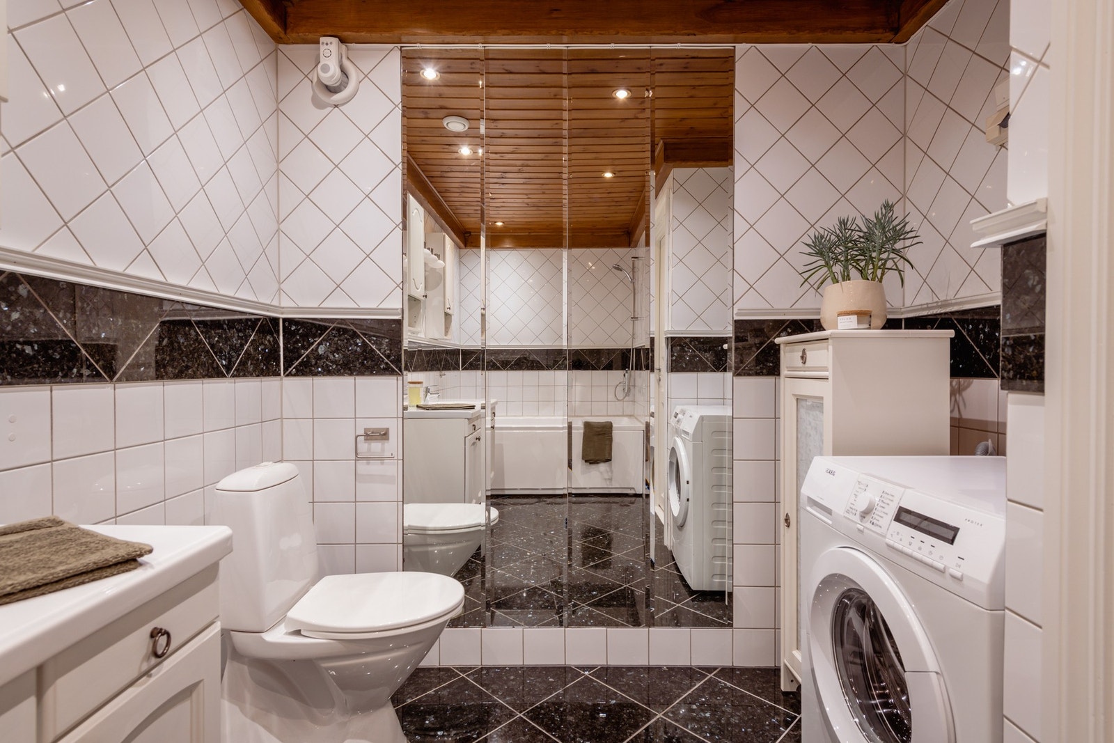 Boligen har et pent flislagt bad med gulvvarme, downlights og helfigurspeil som gir en forstørrende romeffekt. Baderomsinnredningen har profilerte trefronter og består av et skapmøblement med heldekkende servant, overskap og speil. Galleribilde