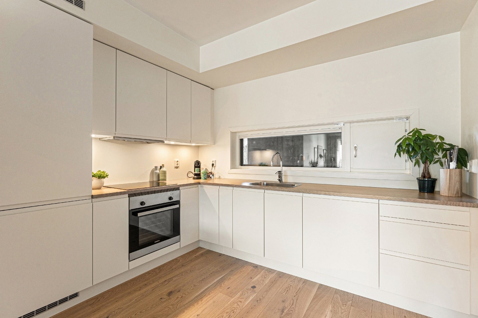 Lekkert HTH-kjøkken med glatte fronter på skap og skuffer, og benkeplate av laminat med nedfelt oppvaskkum Galleribilde