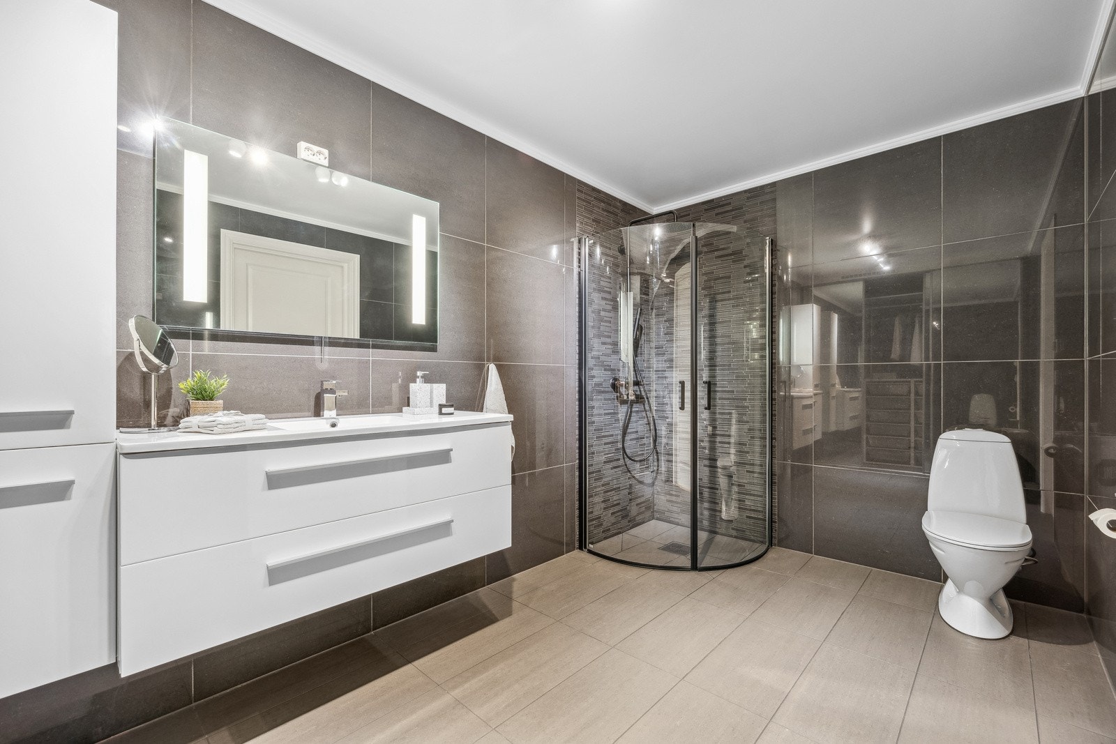 Baderommet har gulvstående toalett og dusjhjørne med innfellbare glassdører, som gir et praktisk og stilrent preg. Galleribilde