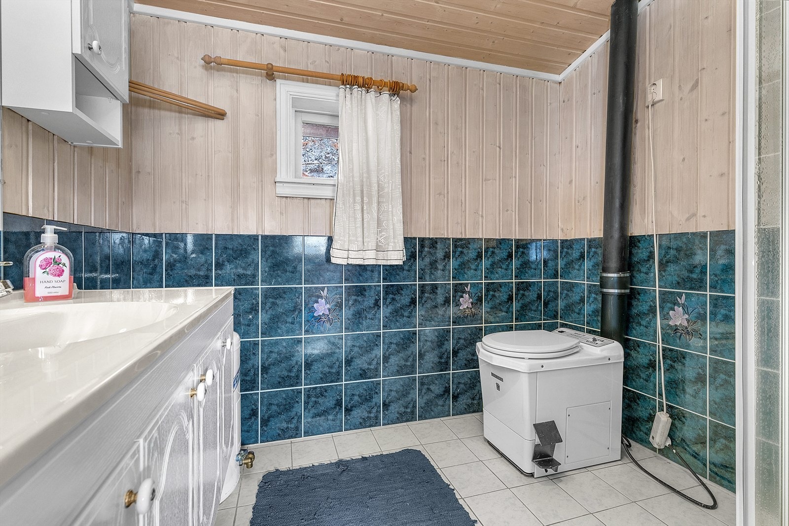 Romslig baderom med servantskap, dusjhjørne og toalett. Galleribilde