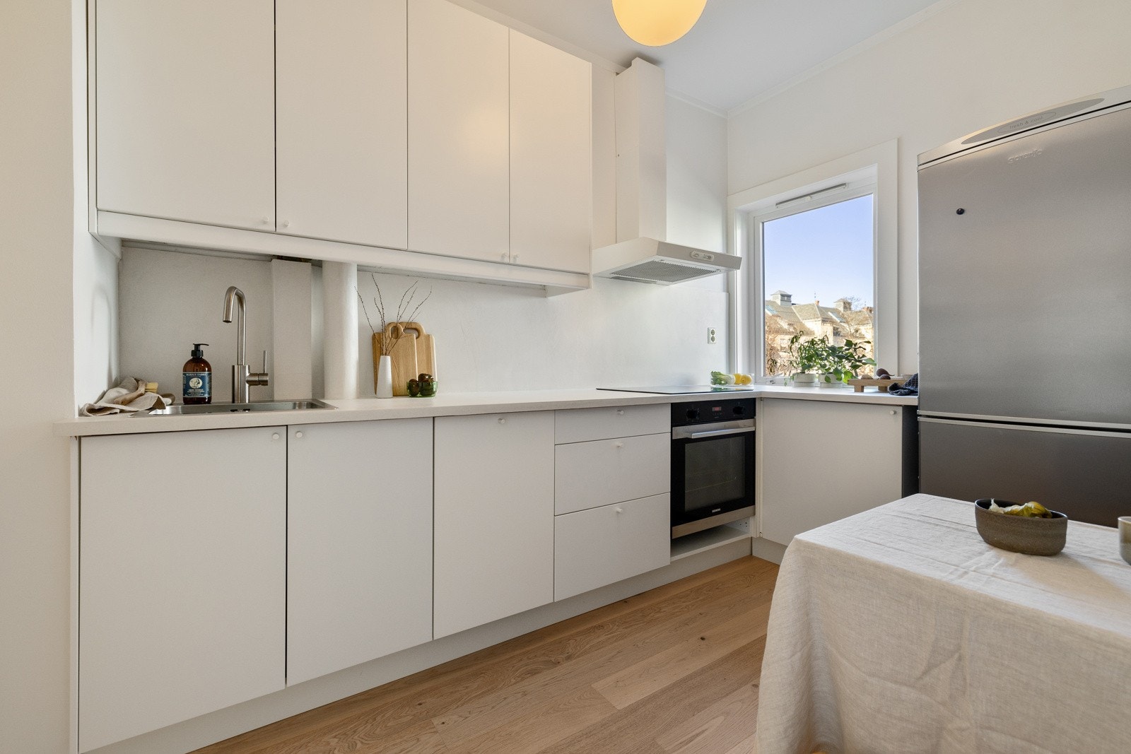 Kjøkkenet har hvite, glatte fronter og en behandlet laminatbenkeplate som gir et moderne og stilrent uttrykk. Galleribilde