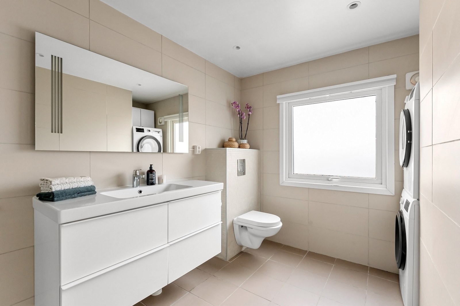 Pent baderom med fliser på gulv med gulvvarme, fliser på vegger og nedsenket himling med downlights Galleribilde