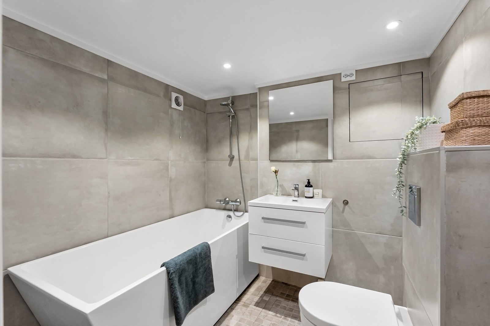 Pent baderom med fliser på gulv med gulvvarme, fliser på vegger og nedsenket himling med downlights Galleribilde