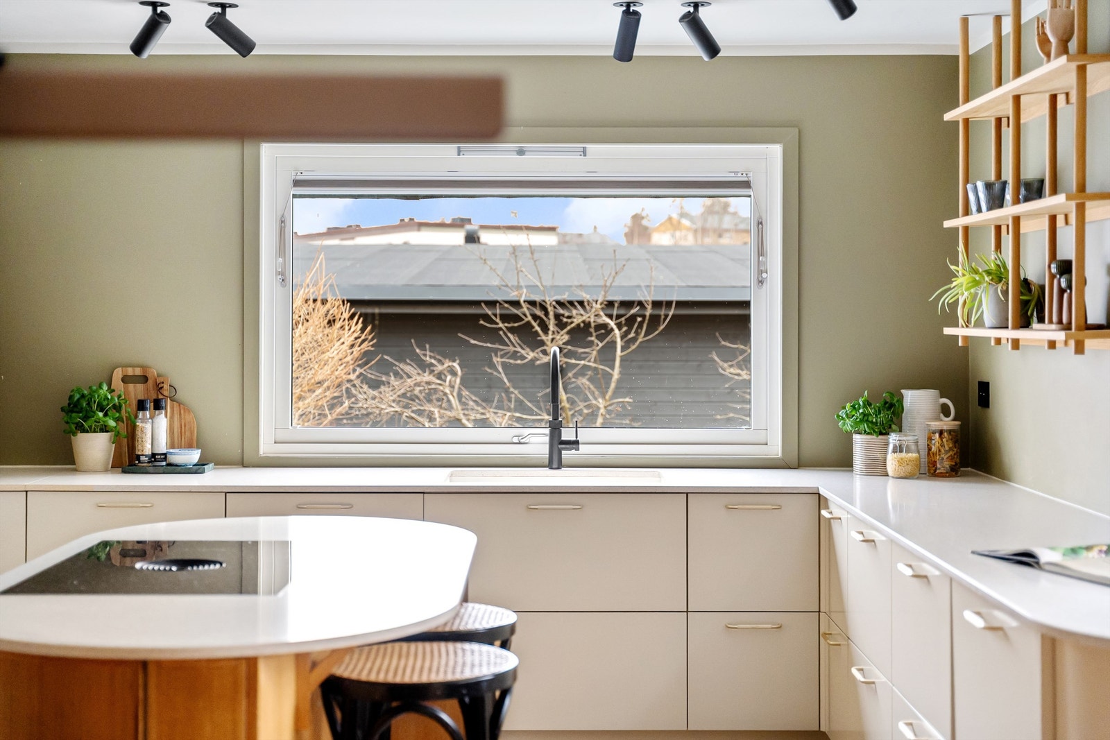 Kjøkkenet har sletter fonter på skap og skuffer og benkeplater av stein med nedfelt oppvaskkum Galleribilde